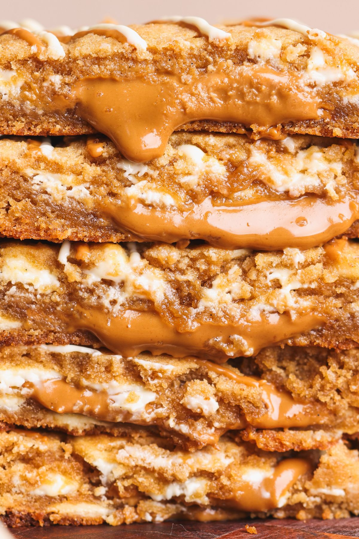 A stack ofbiscoff cookies with biscoff filling oozing out and drizzles of white chocolate.