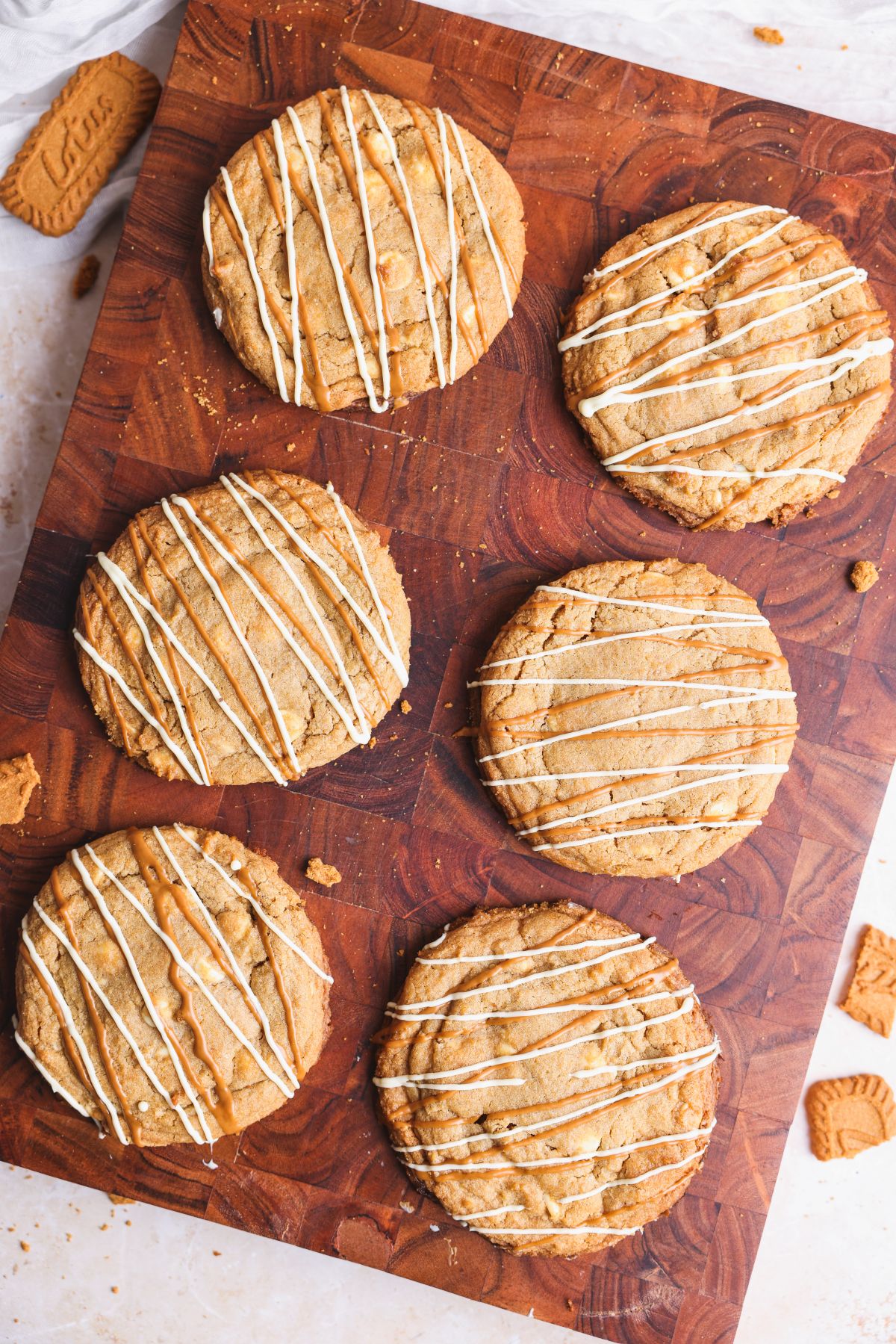 A group of biscoff cookies with white chocolate drizzled icing.