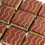 Nine square dubai chocolate brownies with glossy chocolate ganache, each topped with a green wavy line pattern. The pastries have visible layers including a light green and a dark brown layer.