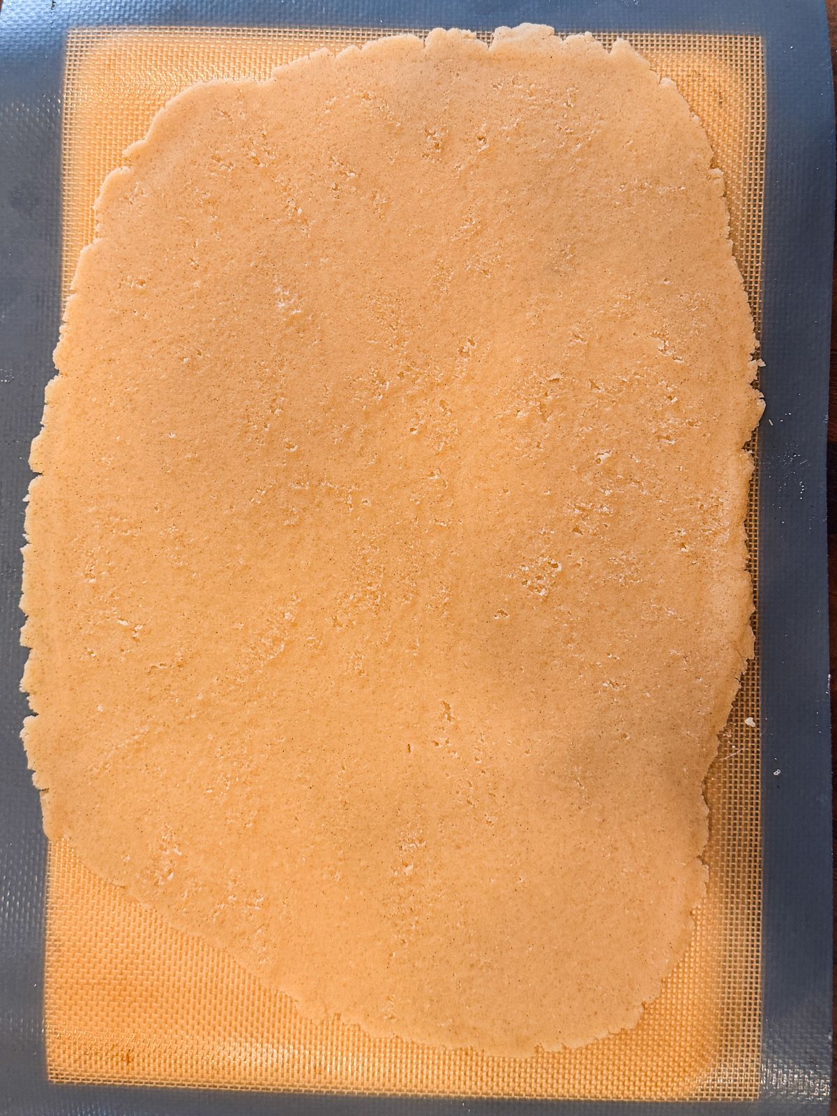 A large, rolled sheet of crauqelin rests on a silicone baking mat.