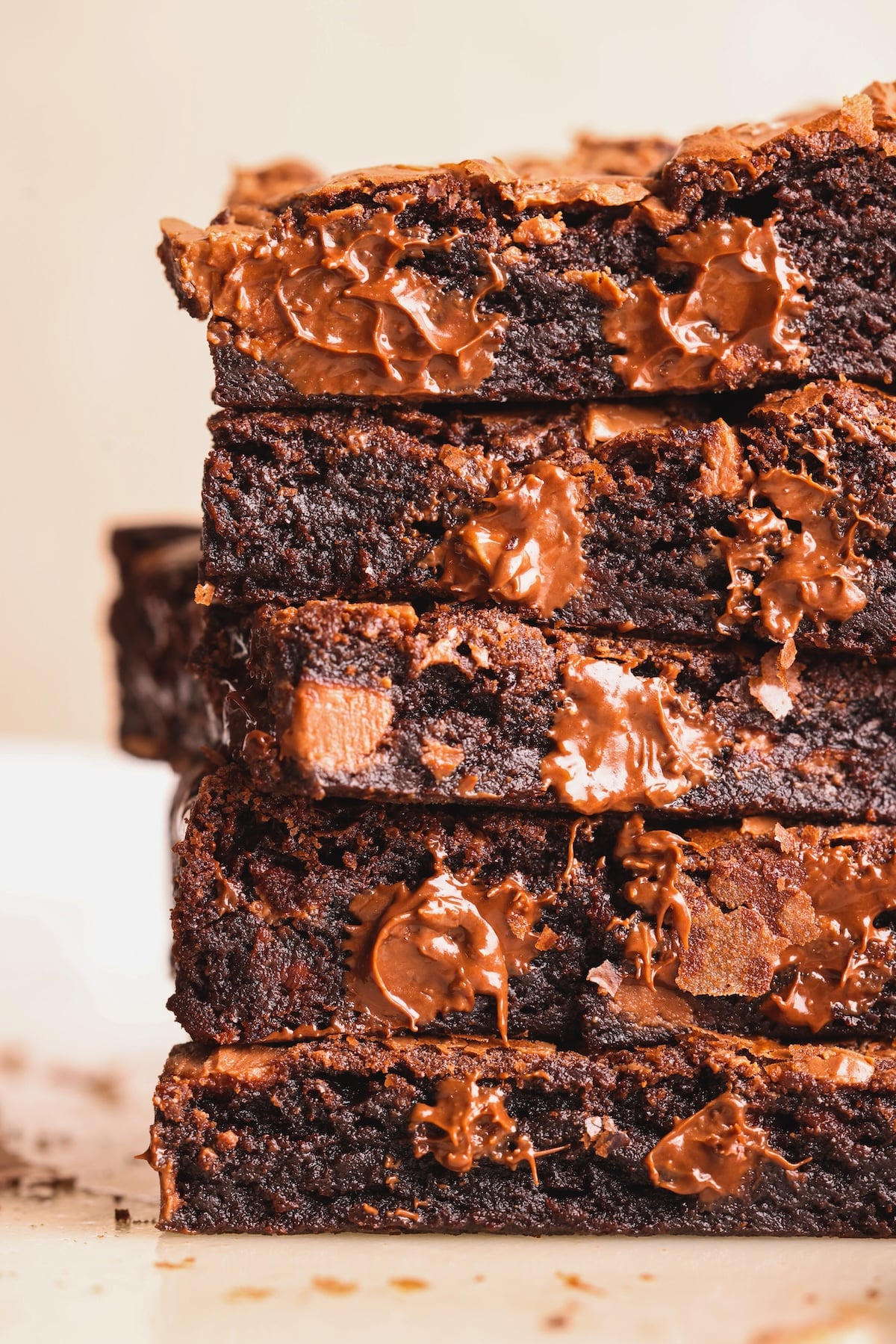 A close-up of a stack of rich chocolate brownies with melted chocolate chips, showing their gooey texture and dense, moist interior.
