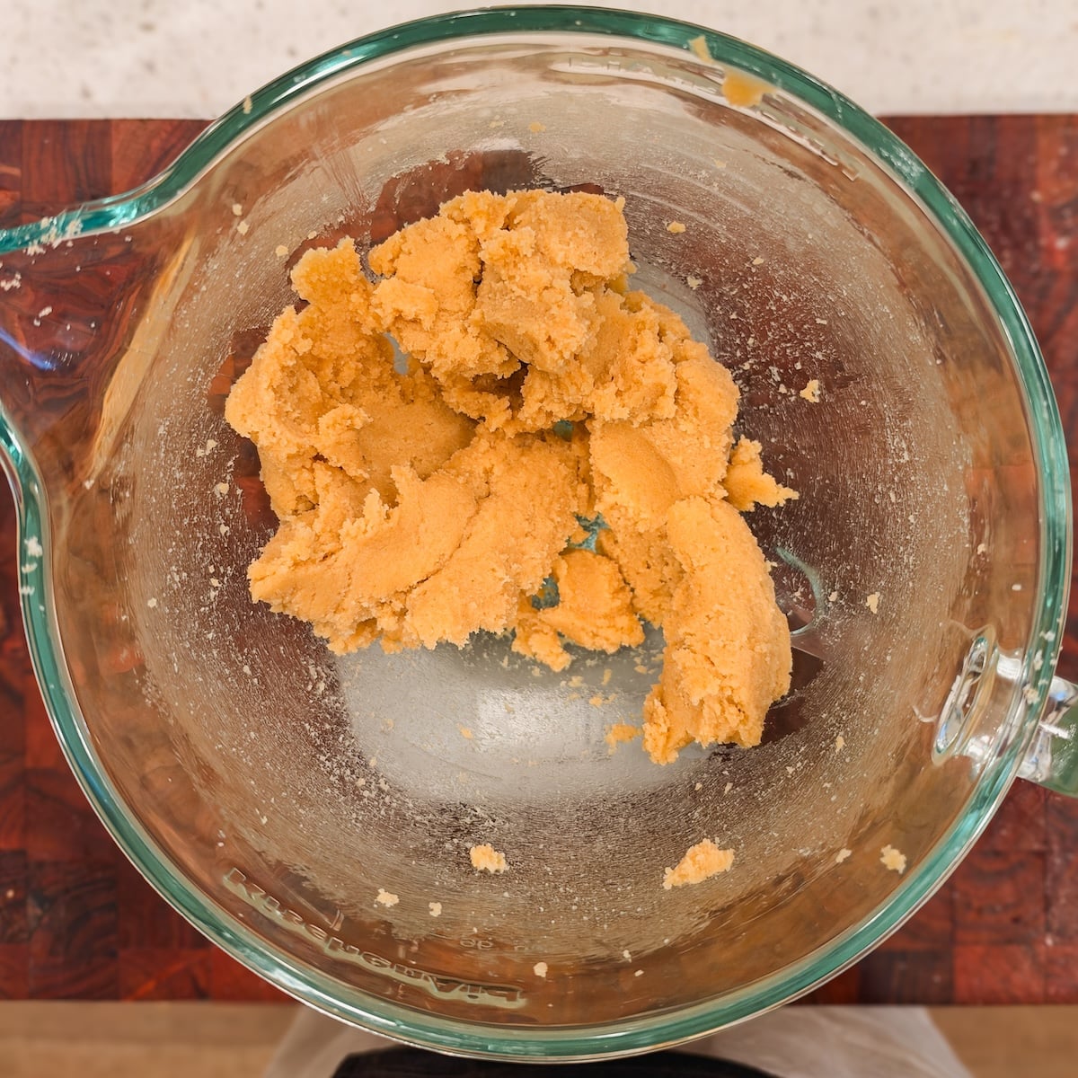 A glass bowl containing a mound of butter and sugar mixed together