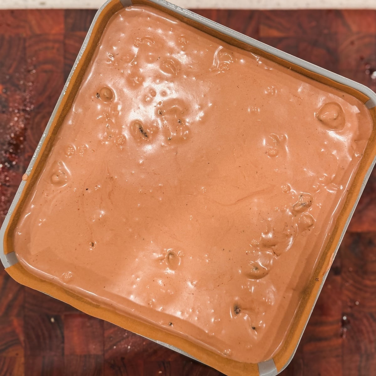 A square metal pan filled with smooth, brown no churn chocolate ice cream base