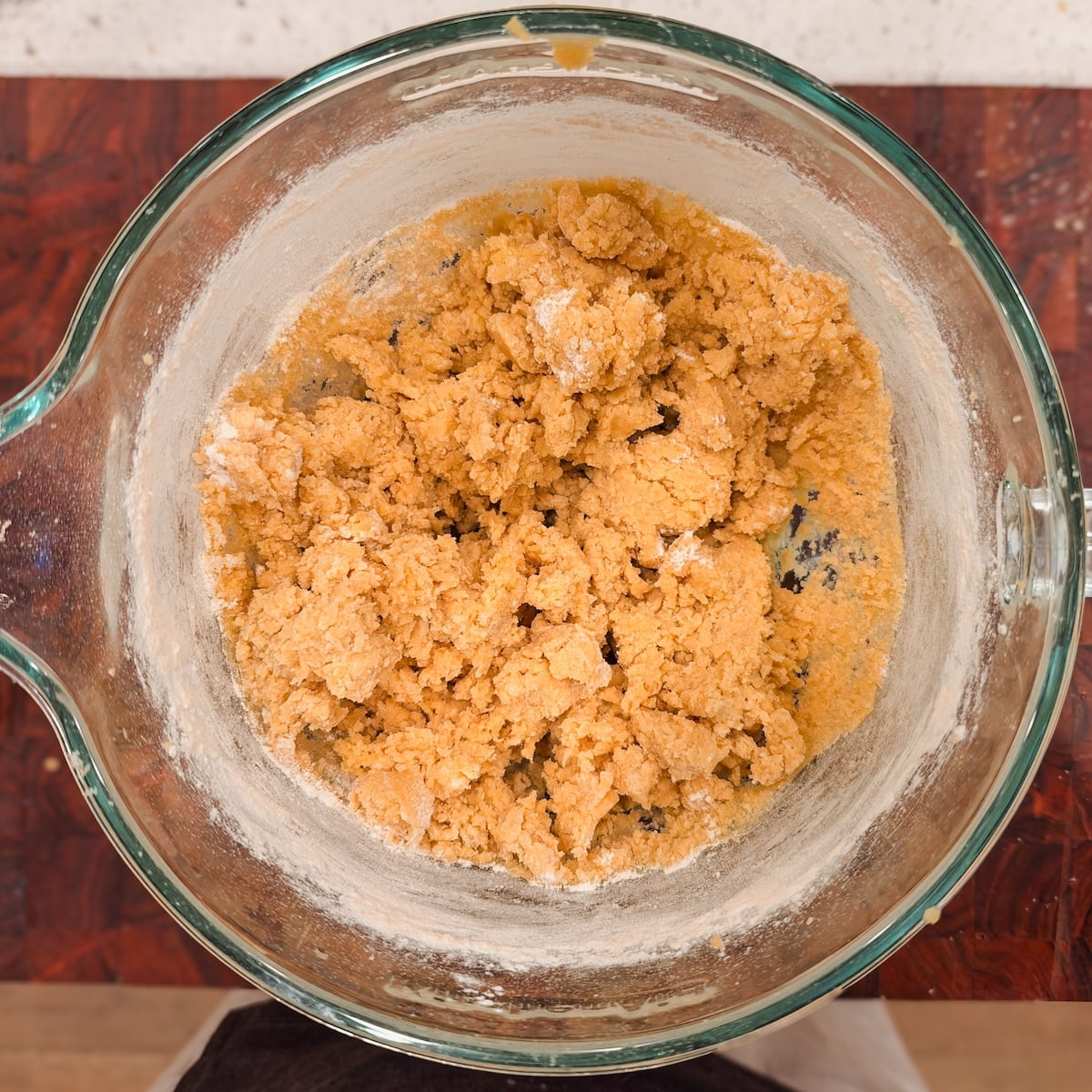 A glass bowl containing a crumbly, unbaked dough mixture