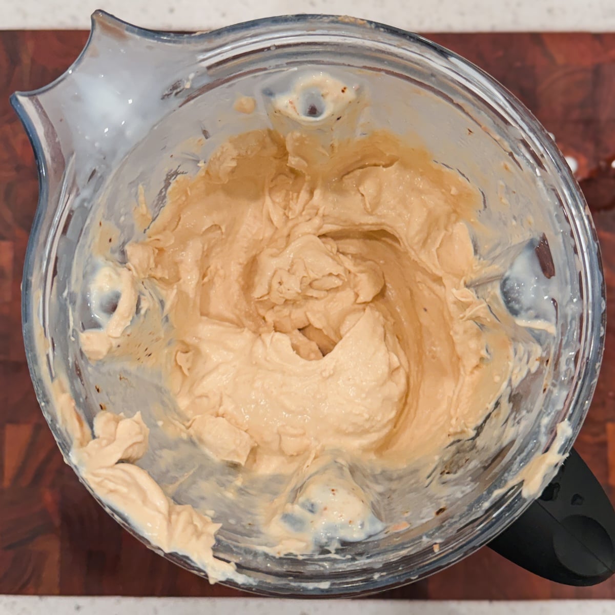 A blender jar containing a thick, creamy beige mixture.