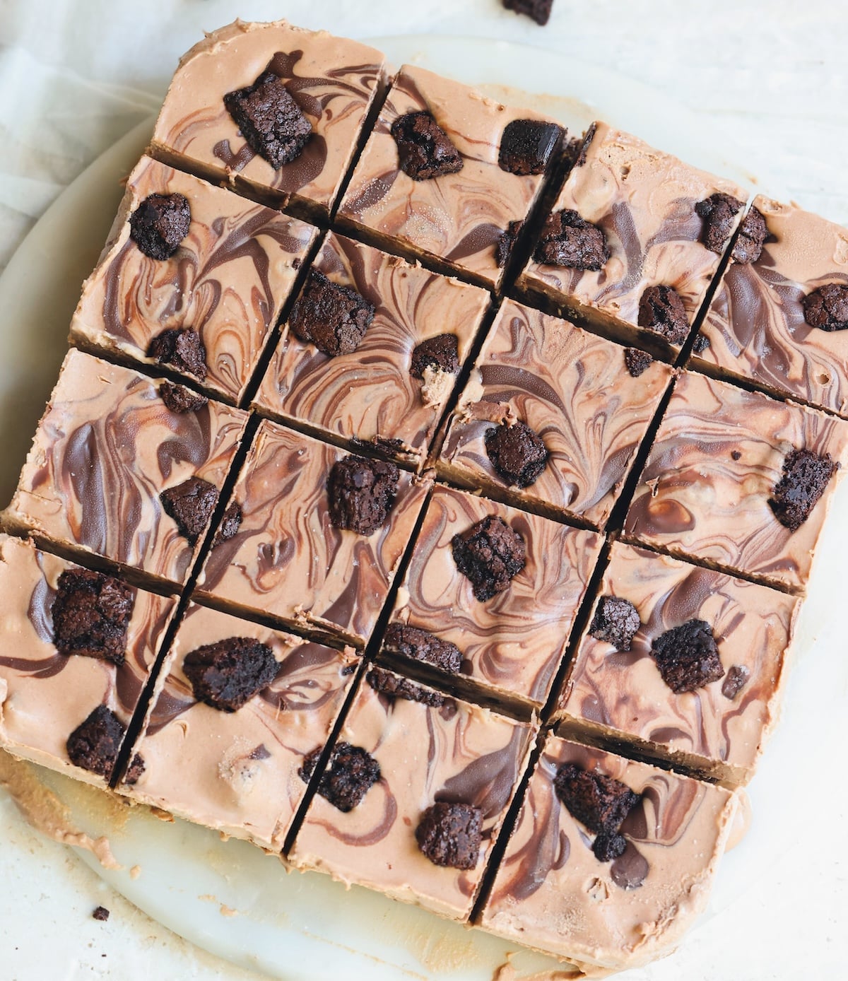 Square pan of marbled chocolate brownie ice cream cut into sixteen equal squares.